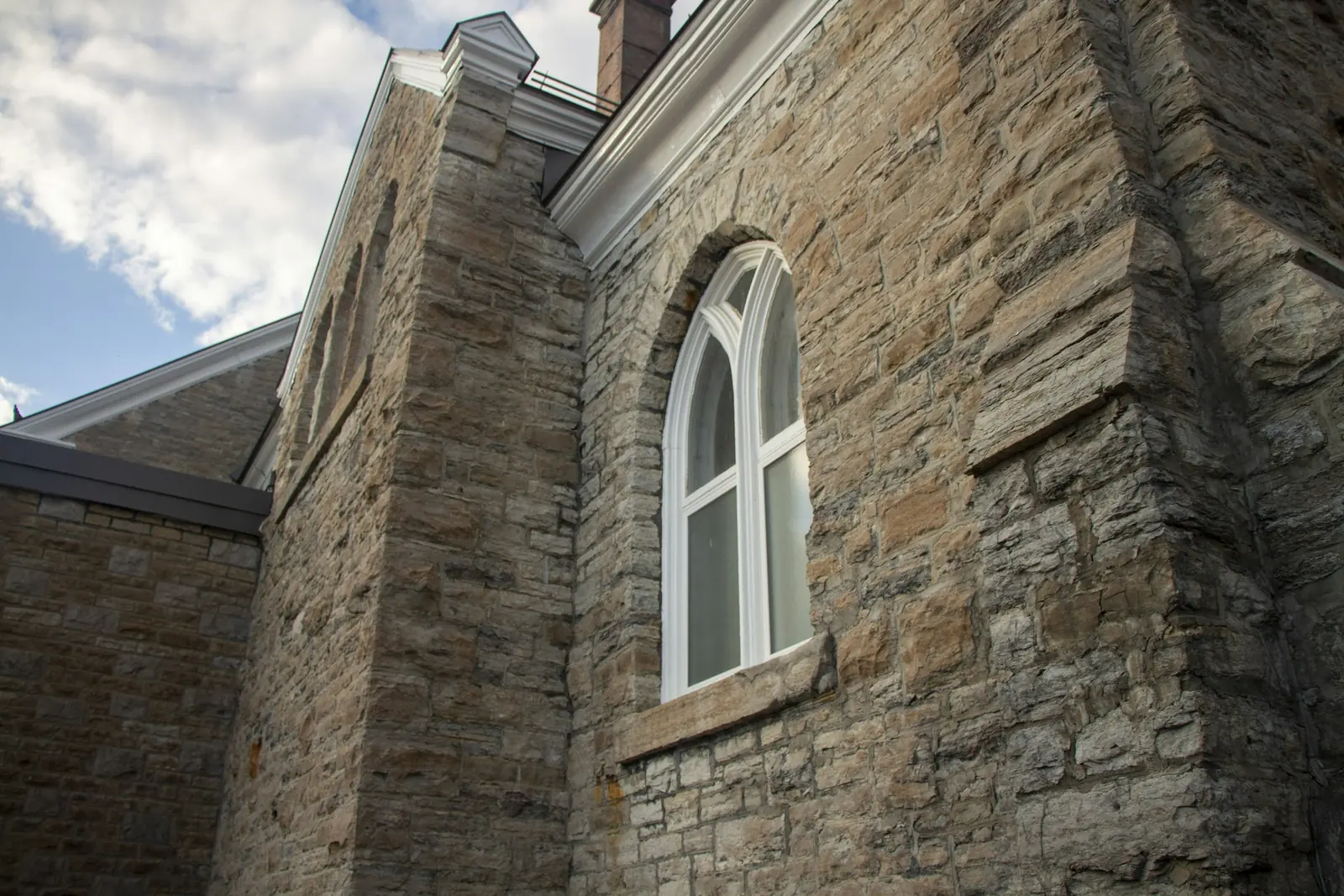 White paint picks out the frame of a pointed-arch window set in rough coursed stone.